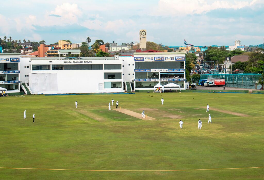 Cricket ground during a live match with players fielding on a green pitch
